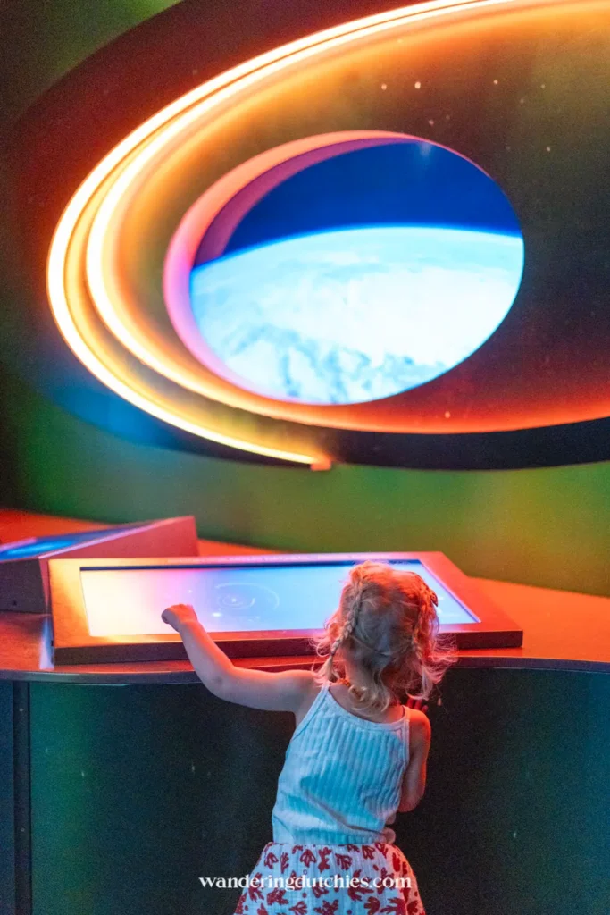 Klein kind bekijkt ruimte-expositie met lichtgevende planeten in Universeum Göteborg.
