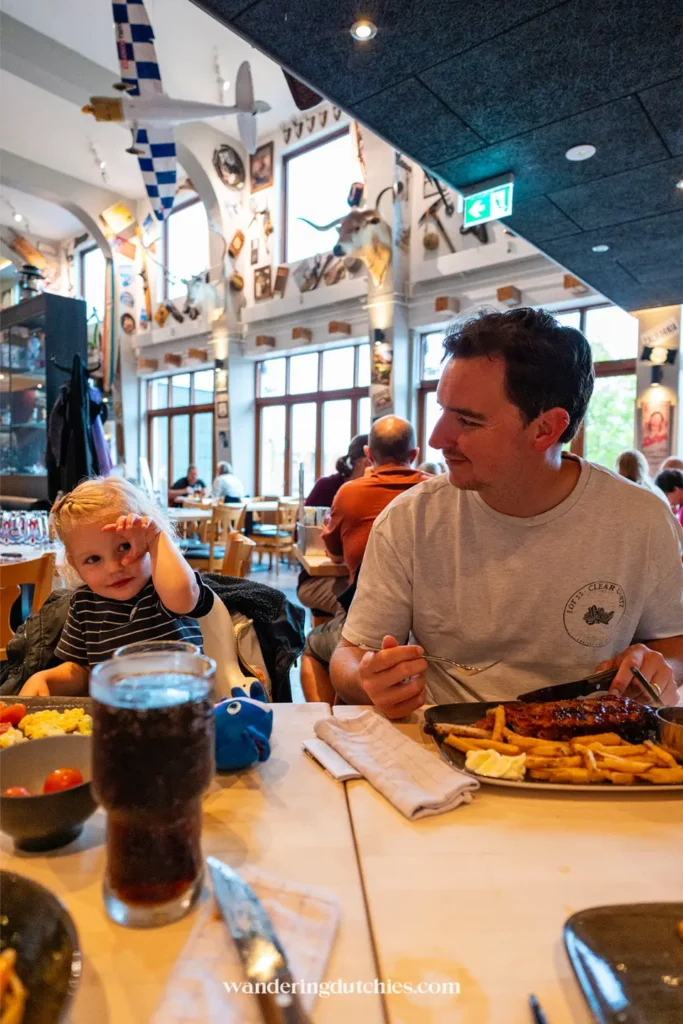 Vader en kind eten bij Bone’s Restaurant in Kolding, Denemarken, met spareribs en friet op tafel