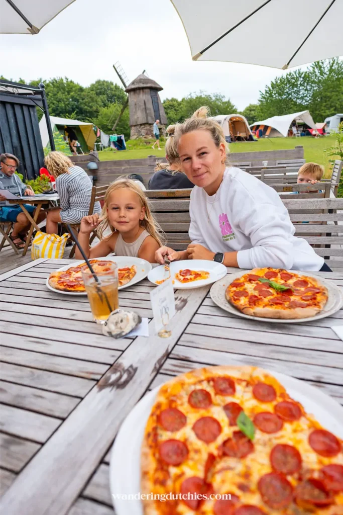 Moeder en kind eten pizza op een terras bij een camping in de buurt van Møns Klint in Denemarken