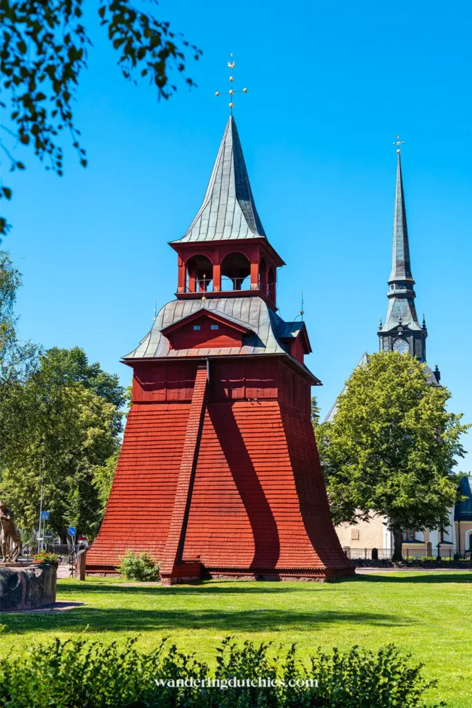 Rode houten klokkentoren in Mora, Zweden, met kerkspits op de achtergrond