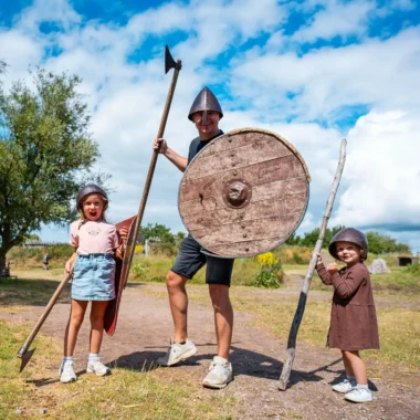 Vader en twee kinderen verkleed als vikingen bij een vikingmuseum in Zuid-Zweden tijdens een roadtrip door Zweden