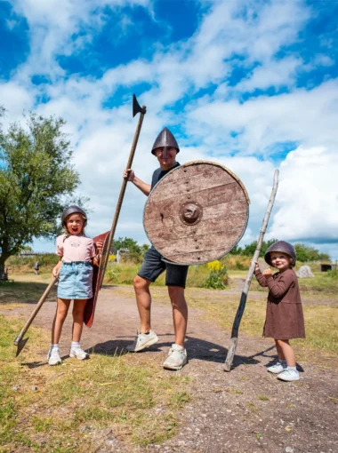 Vader en twee kinderen verkleed als vikingen bij een vikingmuseum in Zuid-Zweden tijdens een roadtrip door Zweden