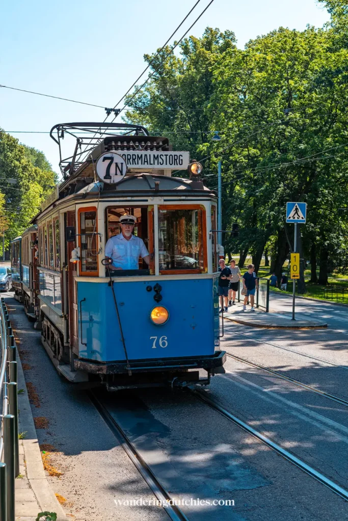 Historische blauwe tram in Stockholm tussen het groen, typisch vervoer tijdens een stedentrip in Zweden