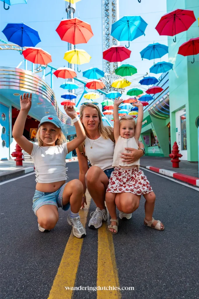 Moeder met twee kinderen onder kleurrijke paraplu’s in pretpark Gröna Lund in Stockholm