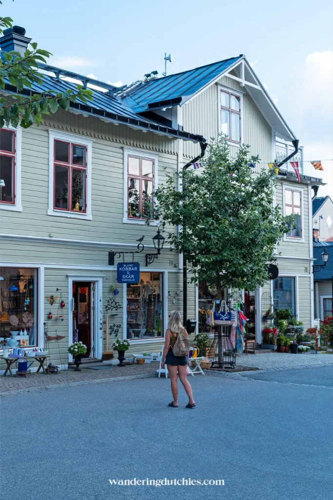Straat in Vaxholm met houten huizen, boetiekjes en een reiziger die rondkijkt in het centrum van de archipelstad