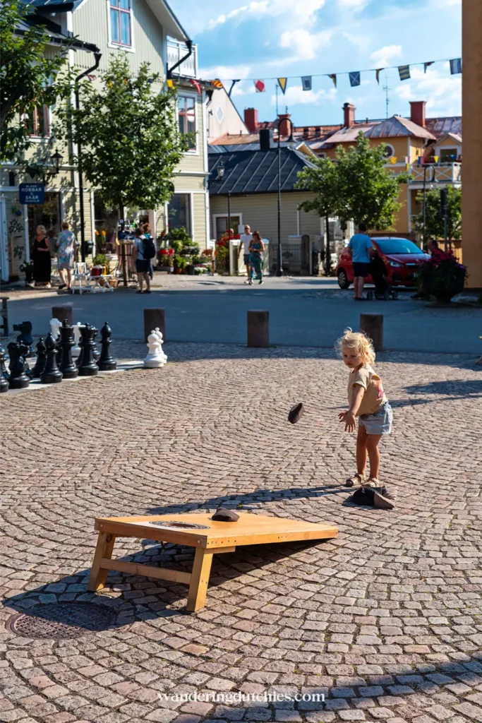 Kind speelt een spel op het plein in Vaxholm met gekleurde huizen en Zweedse sfeer op de achtergrond