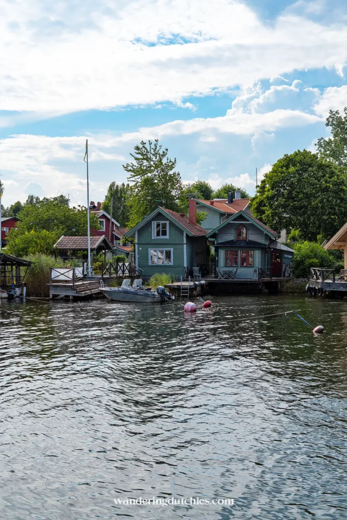 Kleurrijke houten huizen aan het water in Vaxholm met bootjes en groene tuinen langs de oever