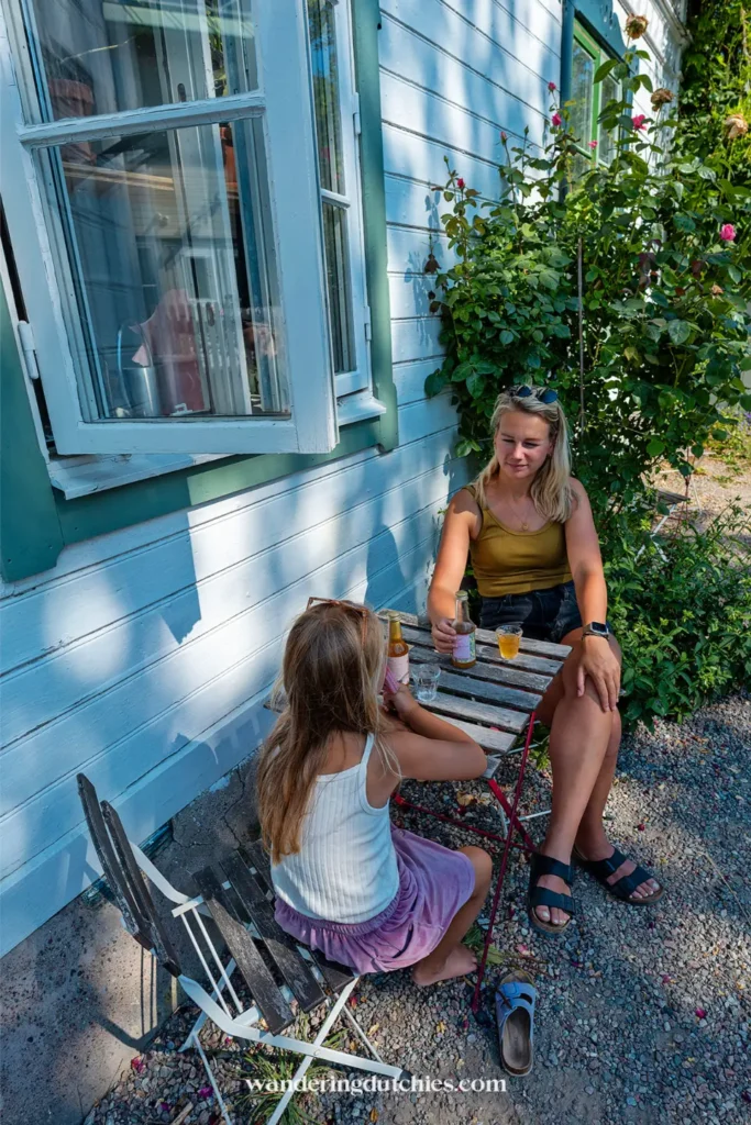 Moeder en kind zitten aan een tafeltje buiten bij Camilles Trädgård & Café in Vaxholm tijdens een zomerse pauze