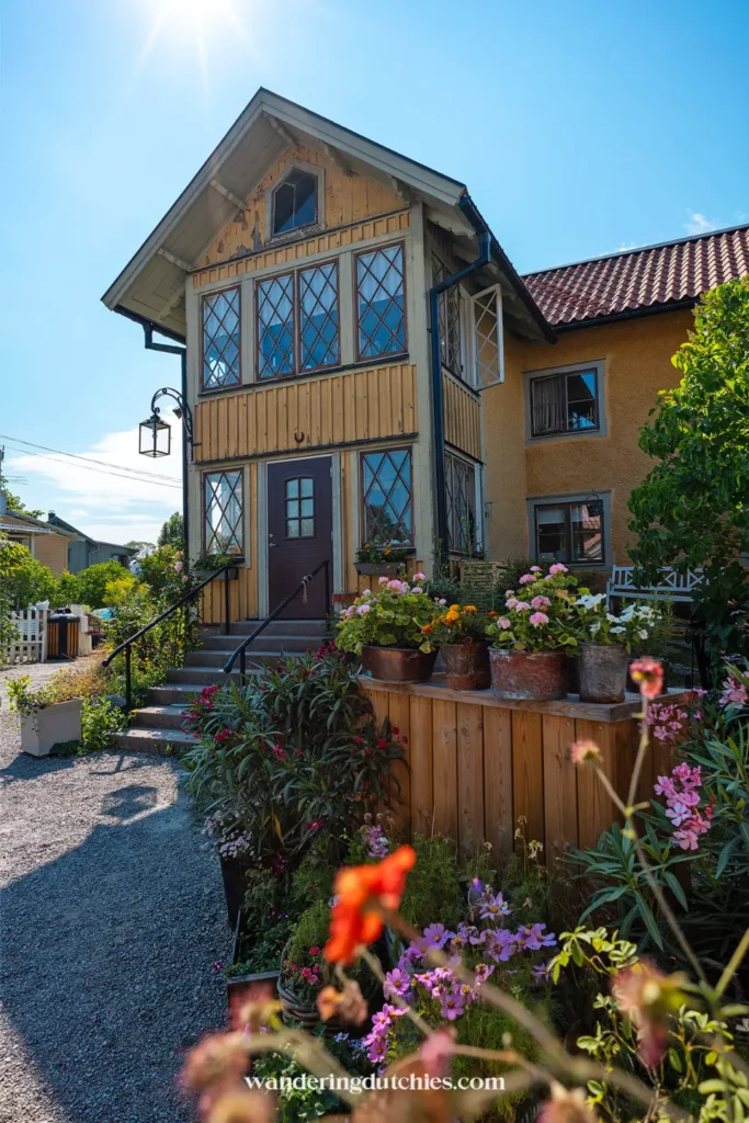 Traditioneel houten huis in Vaxholm met bloemen voor de deur en zonnige zomerdag in Zweden