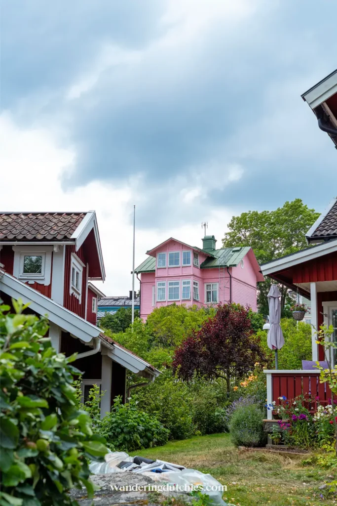 Pastelroze houten huis tussen tuinen in Vaxholm, Zweden