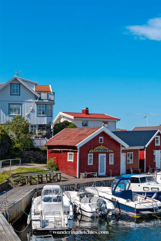 Rode houten huisjes en motorbootjes in de haven van Åstol, Zweden, aan de westkust