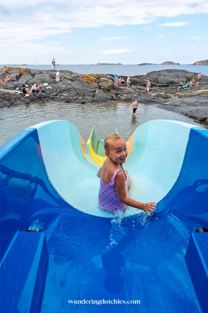 Kind glijdt van een waterglijbaan direct de zee in bij een zwemplek op Åstol, Zweden