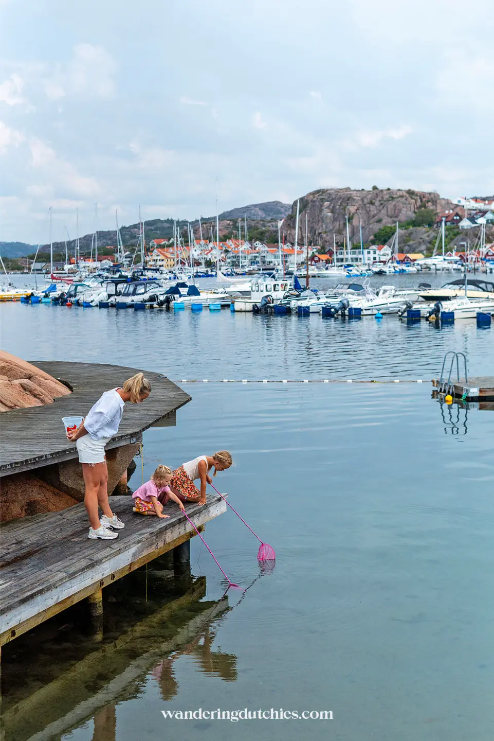 Moeder en kinderen krabben vangen vanaf steiger bij rustige haven in Zweden