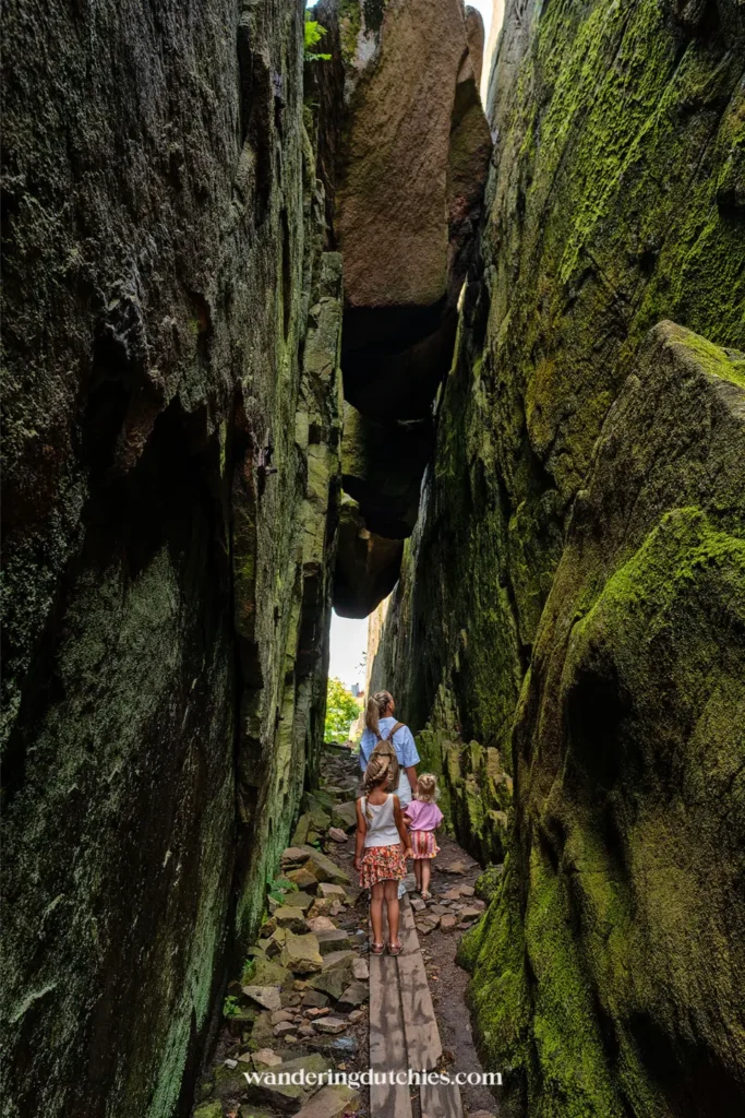 Moeder en kinderen lopen door smalle kloof tussen hoge rotswanden in Fjällbacka