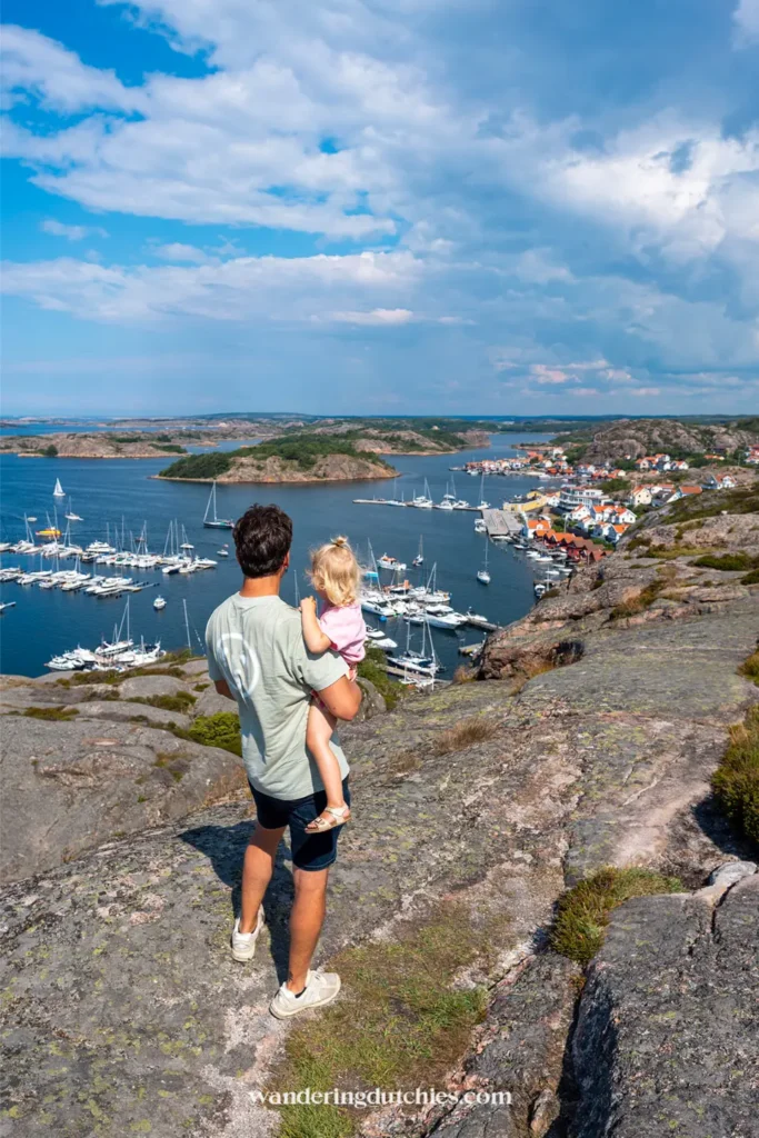 Vader met kind op arm kijkt uit over haven en eilanden aan de Zweedse westkust