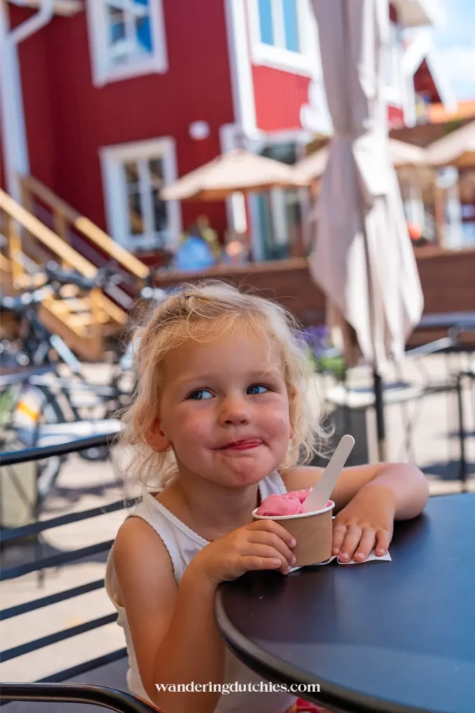 Kind eet roze ijsje op terras in Smögen