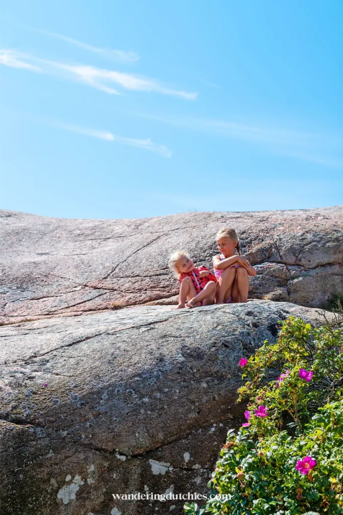 Twee kinderen zitten op rotsen met uitzicht over de Zweedse westkust