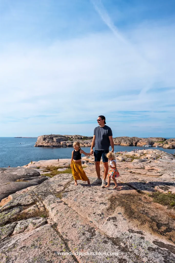 Vader met twee kinderen op de rotsen met uitzicht op zee bij Smögen aan de westkust van Zweden