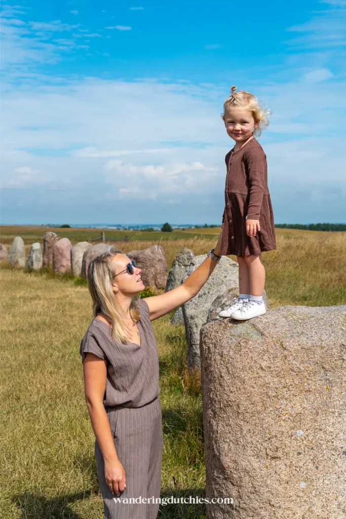 Moeder helpt kind op een grote steen bij Ales Stenar in Zuid-Zweden