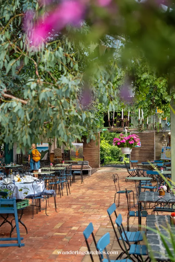 Terras van Backagården in Zuid-Zweden met tafels tussen groen en bloemen