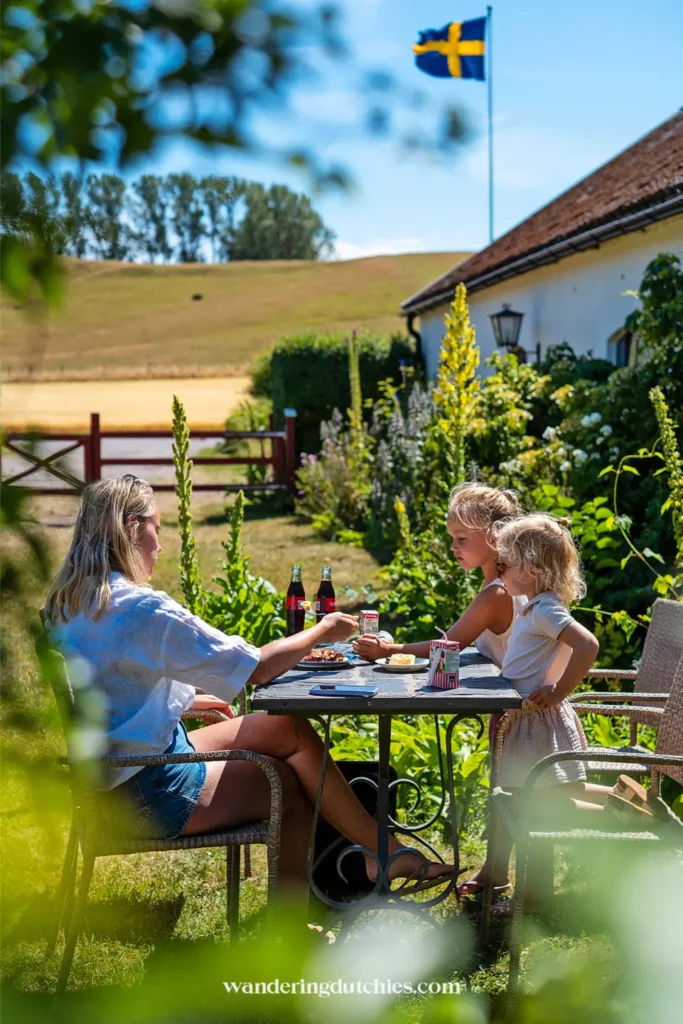 Fika bij Backagården in Zuid-Zweden met moeder en kinderen aan tafel in de tuin