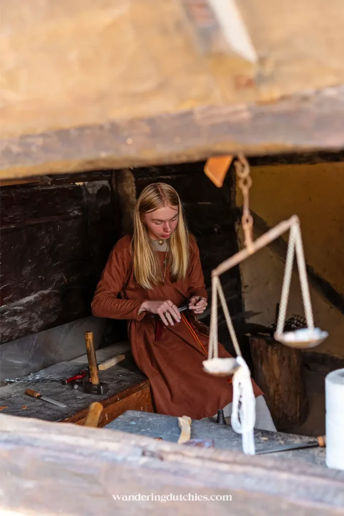 Viking vrouw werkt in een houten huisje in het Foteviken Viking Museum in Zuid-Zweden