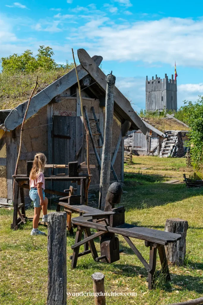Kind bekijkt houten werkbank en hutjes in het Foteviken Viking Museum in Zuid-Zweden