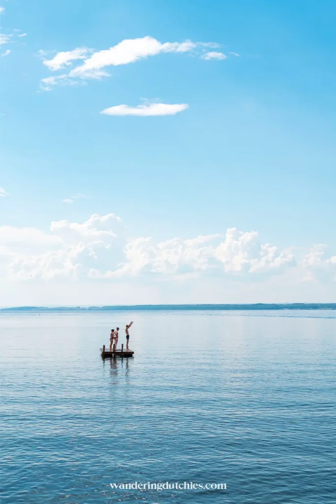 Kinderen staan op een kleine houten steiger in het Vätternmeer bij Gränna onder een heldere blauwe lucht