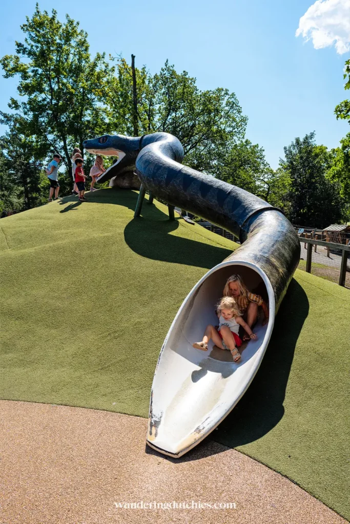 Kinderen glijden van slangvormige glijbaan op speelplek in Stockholm