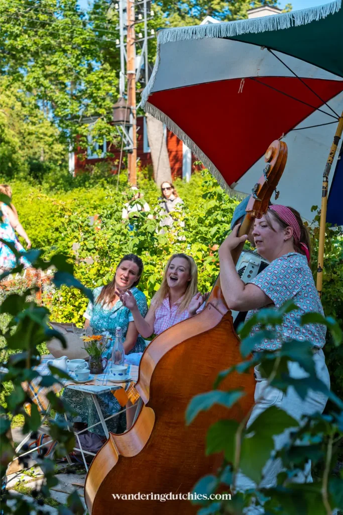 Vrolijke Zweedse muzikanten met contrabas en accordeon spelen buiten in een groene tuinsetting in Skansen in Stockholm