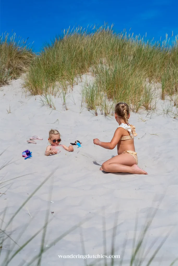 Twee kinderen spelen in het zand tussen de duinen van Sandhammaren strand aan de Zweedse kust