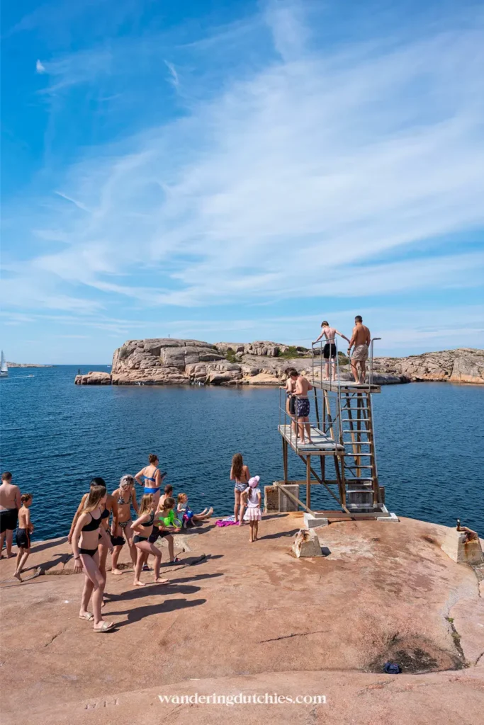 Mensen staan op een metalen springplatform op de rotsen bij Smögen, klaar om in zee te springen