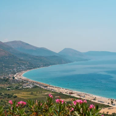 Albanese Rivièra met uitzicht over een lange baai, turquoise zee en stranden bij Dhërmi, met bergen op de achtergrond.
