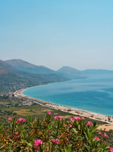 Albanese Rivièra met uitzicht over een lange baai, turquoise zee en stranden bij Dhërmi, met bergen op de achtergrond.