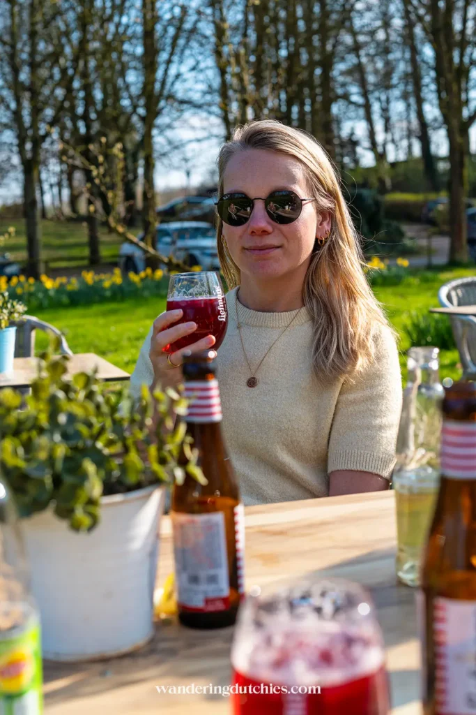 Vrouw met drankje op terras tussen de boomgaarden in Borgloon.
