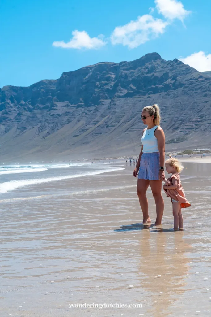 Moeder en kind wandelen langs strand van Famara op Lanzarote.