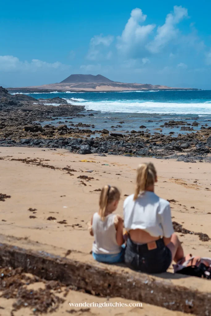 Moeder en kind kijken uit over een ruig strand op Lanzarote.