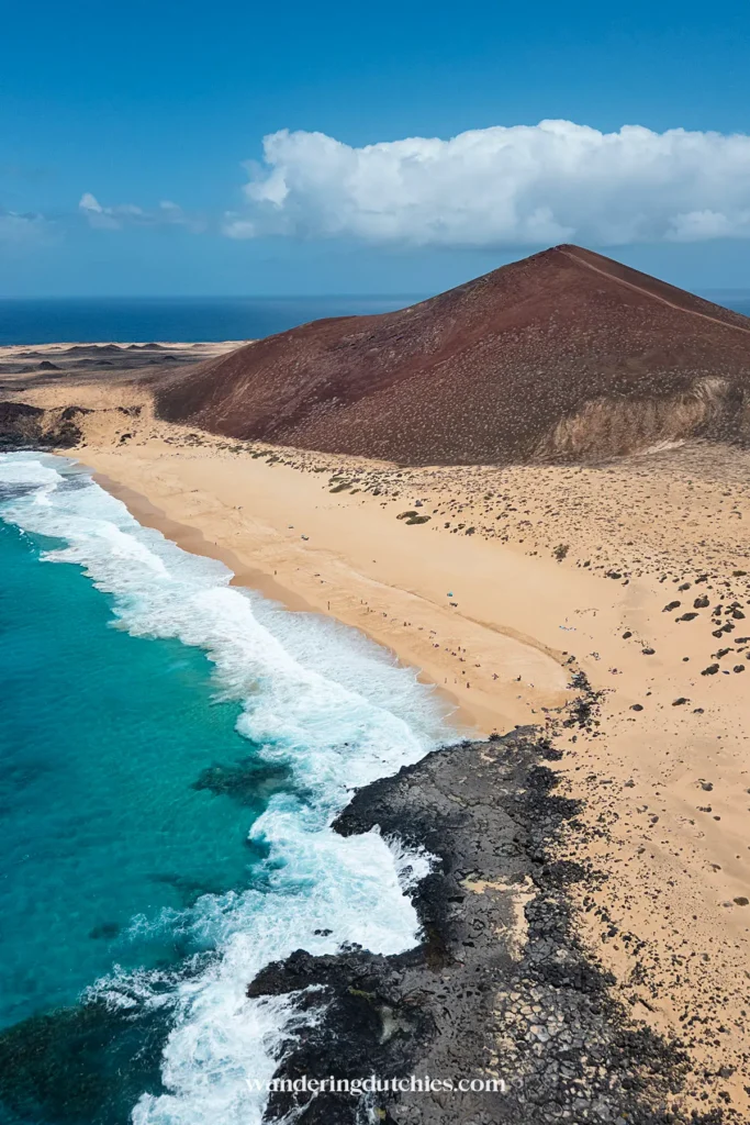 Playa de las Conchas met turquoise zee en vulkanisch landschap op La Graciosa.