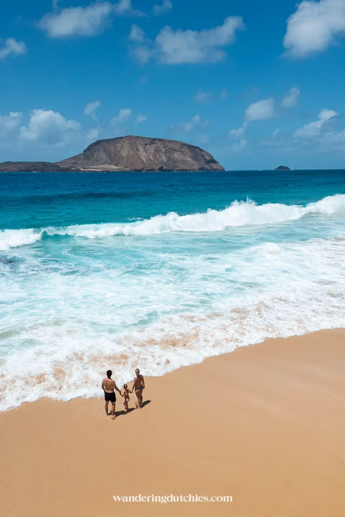 Gezin staat bij de golven op een strand op La Graciosa.
