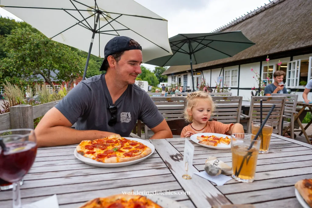 Vader en kind eten pizza op het terras van Camp Møns Klint in Denemarken.