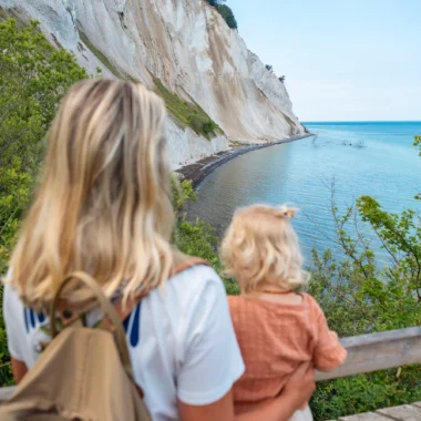 Gezin kijkt uit over de witte krijtrotsen van Møns Klint en de blauwe zee in Denemarken.
