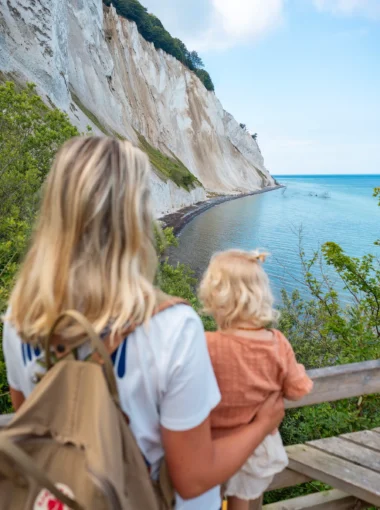 Gezin kijkt uit over de witte krijtrotsen van Møns Klint en de blauwe zee in Denemarken.