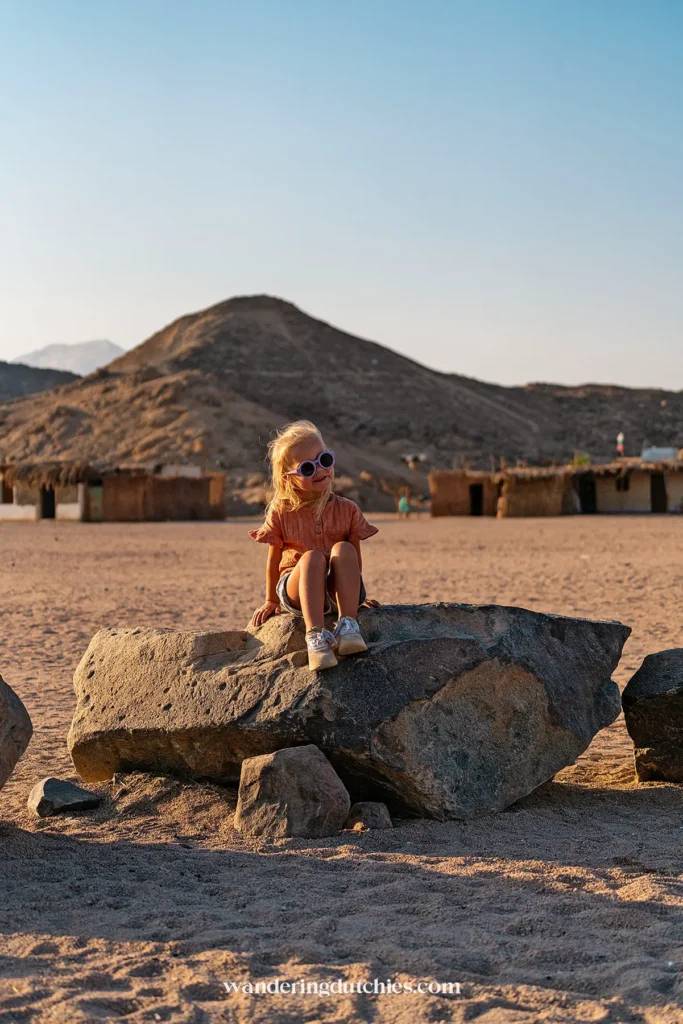 Kind zit op rots in de woestijn van Hurghada, Egypte.