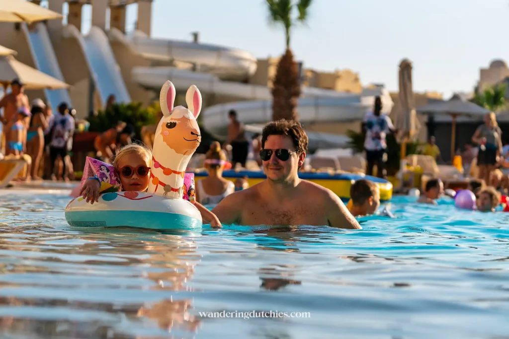 Vader en kind dobberen samen in het zwembad met een opblaasband.