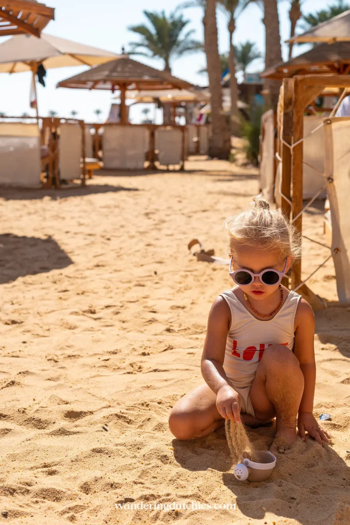 Kind speelt met zand en schepje op het strand bij het resort in Hurgahda.