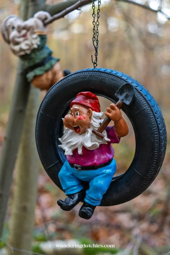 Gnome holding a shovel inside a tire in the forest along the gnome trail in Maria-Hoop, Limburg.