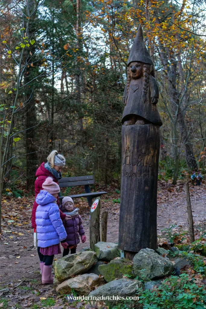Children standing next to a wooden gnome statue at the start of the gnome trail in Maria-Hoop, Limburg.