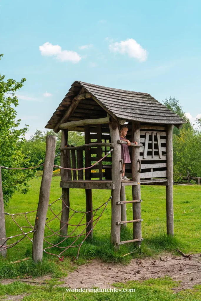 Child playing on a wooden playground structure during a gnome walk in Limburg.