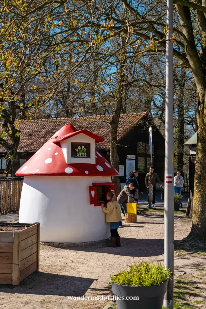 Mushroom-shaped gnome house at the entrance of the Pietersheim Gnome Trail with children playing nearby.