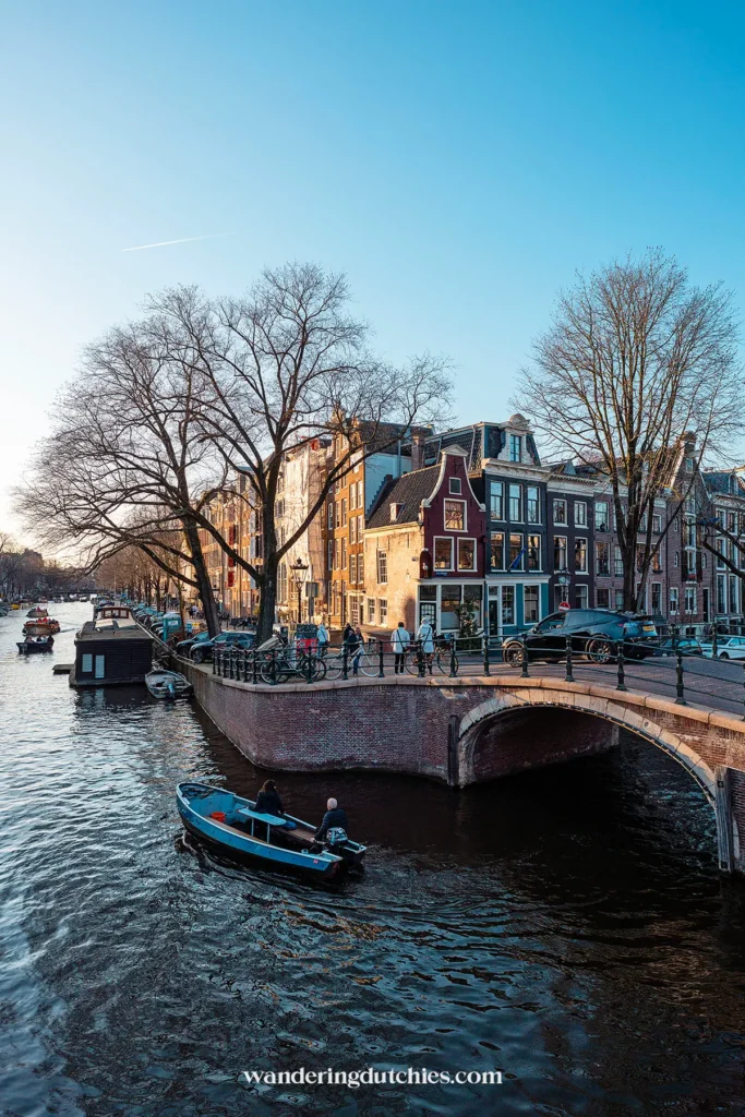 Boat cruising through Amsterdam's canals at sunset